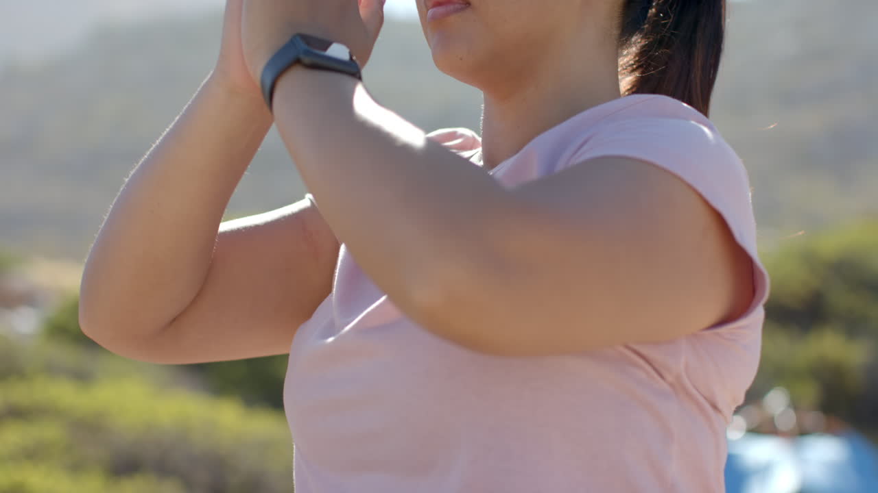 Practicing yoga outdoors during mountain hike, woman wearing smartwatch