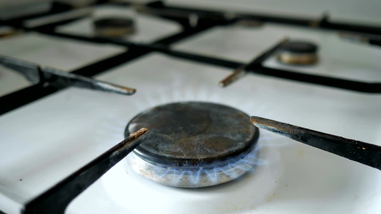 남자의 손은 가스 버너에 불타는 매치를 가져와 가스를 켜니다.