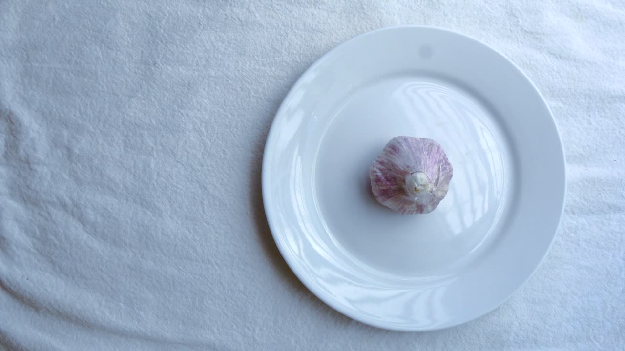Garlic on white ceramic plate on white table mat