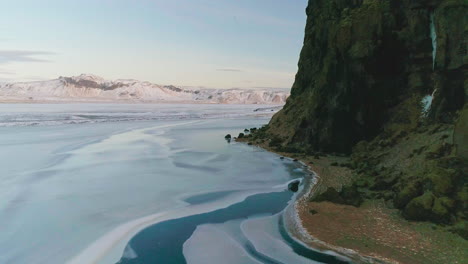 Icy-Mýrdalshreppur-mountain-seascape-aerial-view-flying-across-Vik,-black-sand-volcanic-beach-coastline