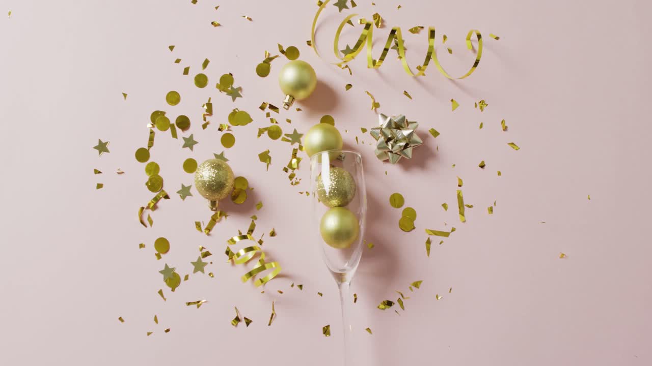 Video di palline decorative dorate in un bicchiere di champagne con stelle filanti e coriandoli su bianco, con spazio per il testo