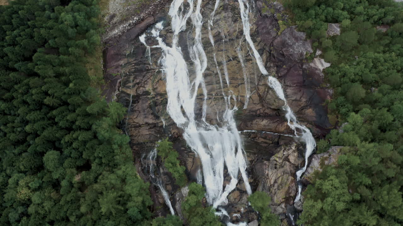 Aerial view of a waterfall cascading through a lush forest