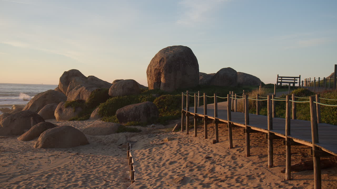 Wooden pathway leading to sandy beach with boulders in Portugal