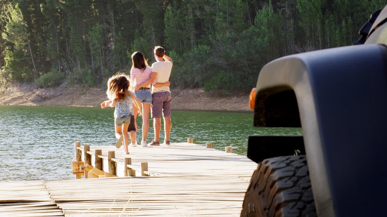I bambini corrono per raggiungere i genitori che ammirano la vista sul lago su un pontile