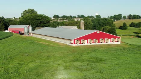 Roter-Hühnerstall,-Schweinestall-Mit-Abluftventilatoren-An-Sommertagen,-Stinkender-Mist-Stört-Nachbarn,-Wohnbebauung-In-Der-Ferne