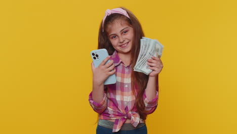 Una-Niña-Sonriente-Y-Feliz-Usa-Un-Teléfono-Inteligente-Regocijándose-Por-Ganar,-Recibiendo-Dinero-En-Efectivo-Del-Premio-Mayor-De-La-Lotería-En-Dólares