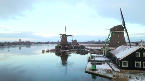 Sereno-Zaanse-Schans-Con-Hermosos-Molinos-De-Viento-Antiguos-Durante-La-Nieve-Del-Invierno,-Antena