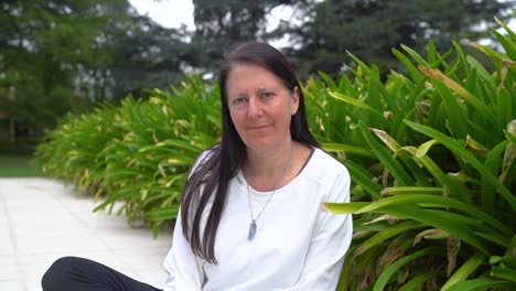 Adult-Woman-Looking-At-Camera-While-Resting-In-The-Garden