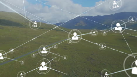 animation of connected icons over aerial view of lush green mountains against cloudy sky