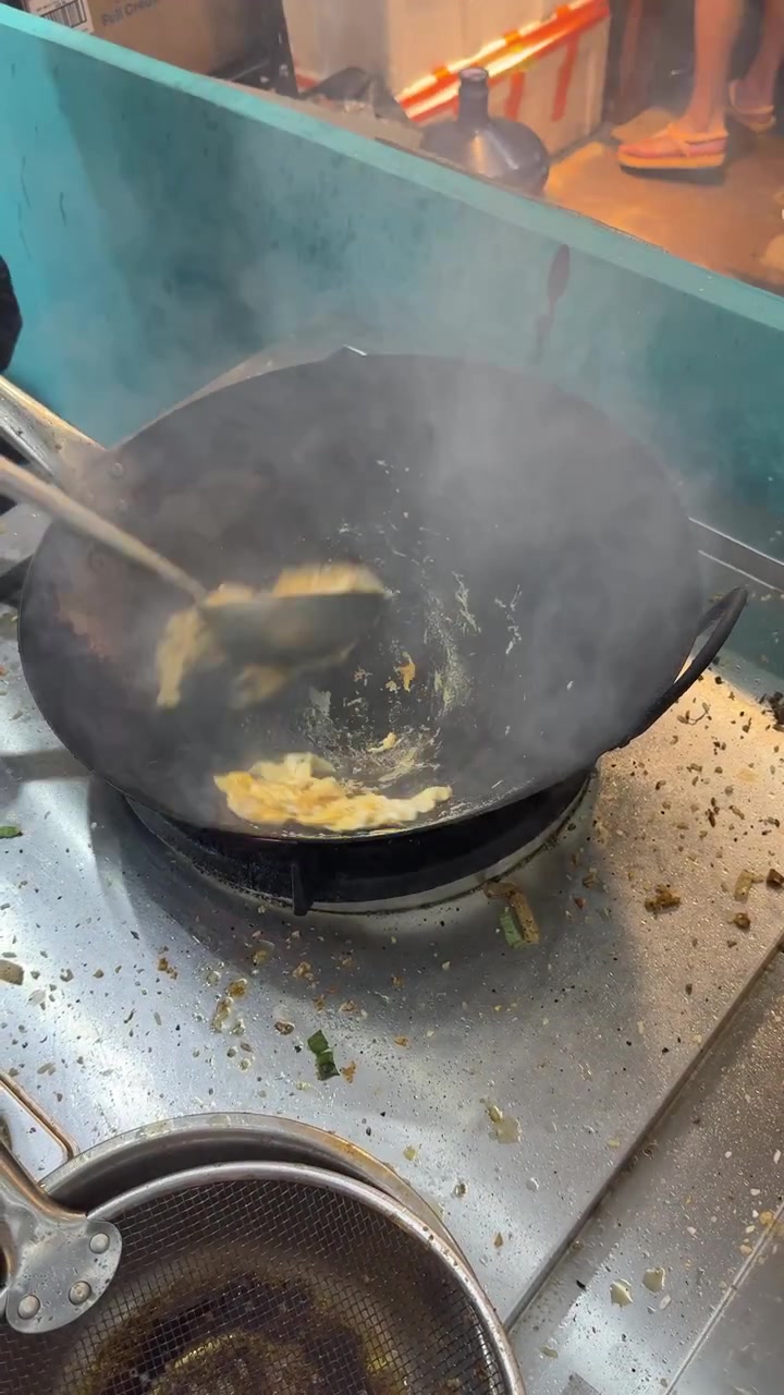 Chef che cucina uova strapazzate in un wok caldo