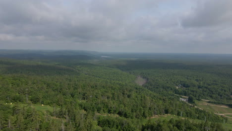 aerial pan of green tree covered mountain and lake. overcast day, calabogie ski hill, ontario canada