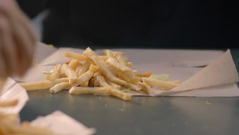 hombre disfrutando de una hamburguesa con papas fritas en papel
