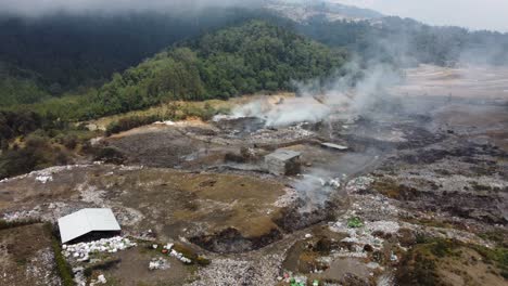 aerial view: trash burns at expansive landfill garbage dump, guatemala