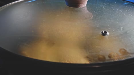 Man-cooking-veggie-patties-and-covering-the-non-stick-frying-pan-with-tempered-glass,-close-up-shot