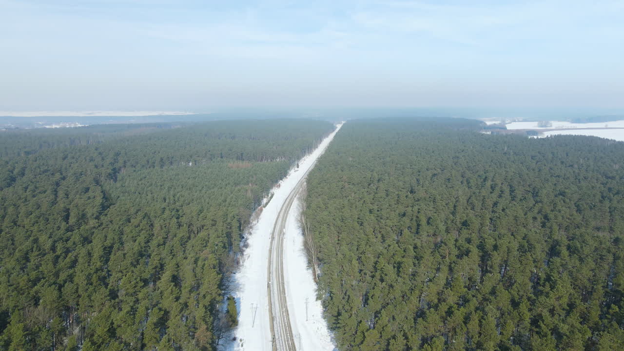 hermosa vía férrea cubierta de nieve a través del bosque de coníferas siempre verde en rakowice, polonia - sobrevuelo lento aéreo