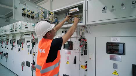 electrical engineer working check the electric current voltage and overload at front of load center cabinet or consumer unit for maintenance in main power distribution system room.