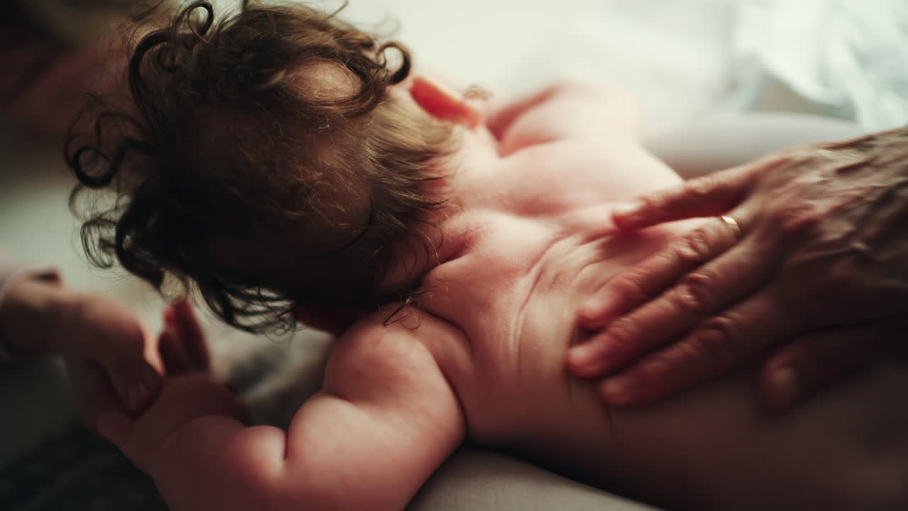 Infant lying on stomach while caregiver gently massages baby's back during wellness routine