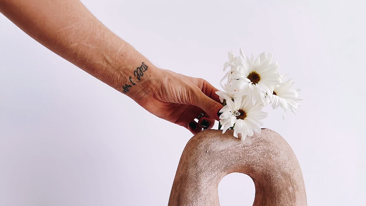 손으로 꽃병에 꽃을 넣는 것