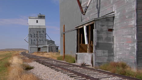 abandoned grain elevators stand along a rusty stretch of railway track