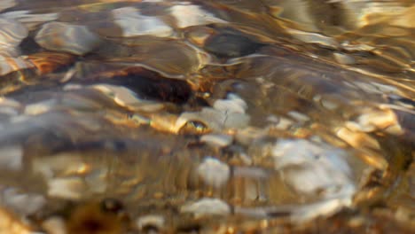 agua clara ondulando sobre las piedras de colores