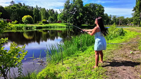 woman fishing by a scenic lake in a summer forest, slow motion