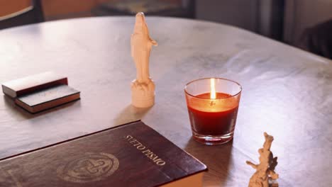 close up 4k video of the holy bible book with statue of the holy mary and candle light next to it