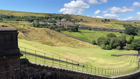 casas de campo rurales en la ladera de una colina en marsden west yorkshire reino unido, rodeadas de colinas y campos al pie de una presa en el embalse de butterley