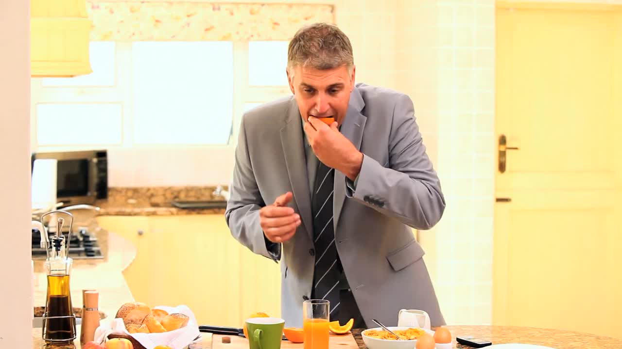 un hombre de negocios en traje tomando apresuradamente su desayuno.