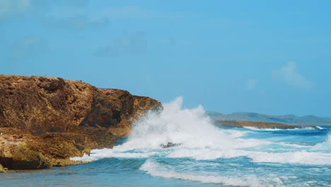 olas rompiendo y rociando rocas de coral en la costa de curacao, cámara lenta
