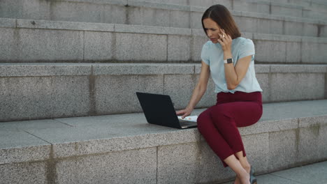 mujer de negocios hablando en un teléfono inteligente al aire libre. mujer trabajando en una computadora portátil
