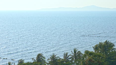 Across-an-ocean,-bay-are-distant-mountains-covered-in-mist