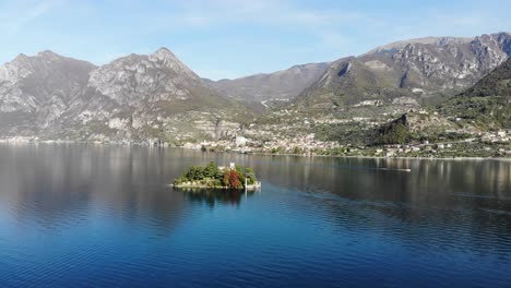 drone slowly approaches loreto island with a autumn panorama lake on the backside