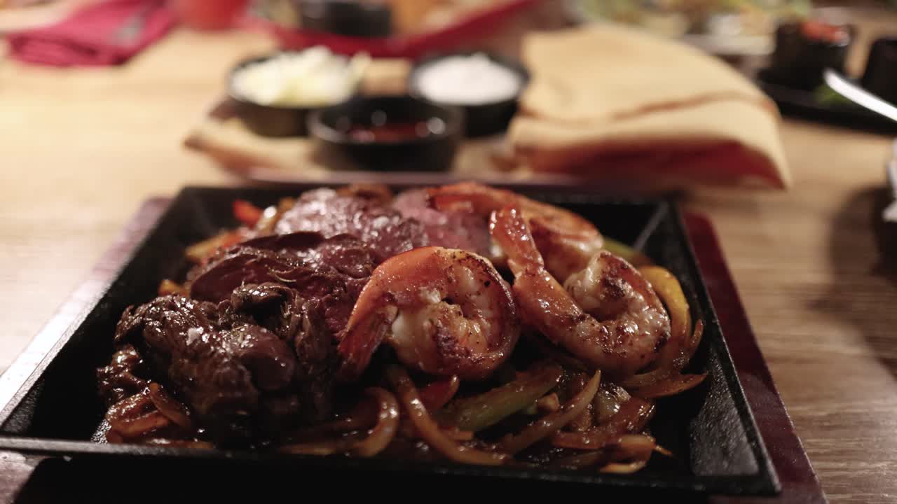 A hot plate of sizzling prawns and shrimp with vegetables, set in a warm, inviting dining environment