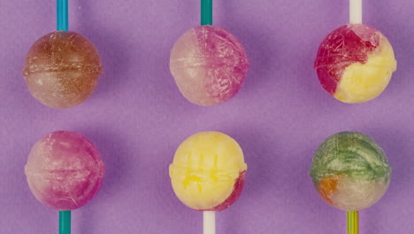 sweet lollipops on color purple background zoom frame . bright texture sugar candies close up top view. composition of favorite children's summer sweets. studio shot for shop, supermarket, confectionery