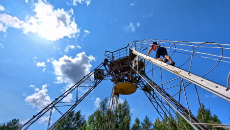 man climbing a tall rusty metal tower