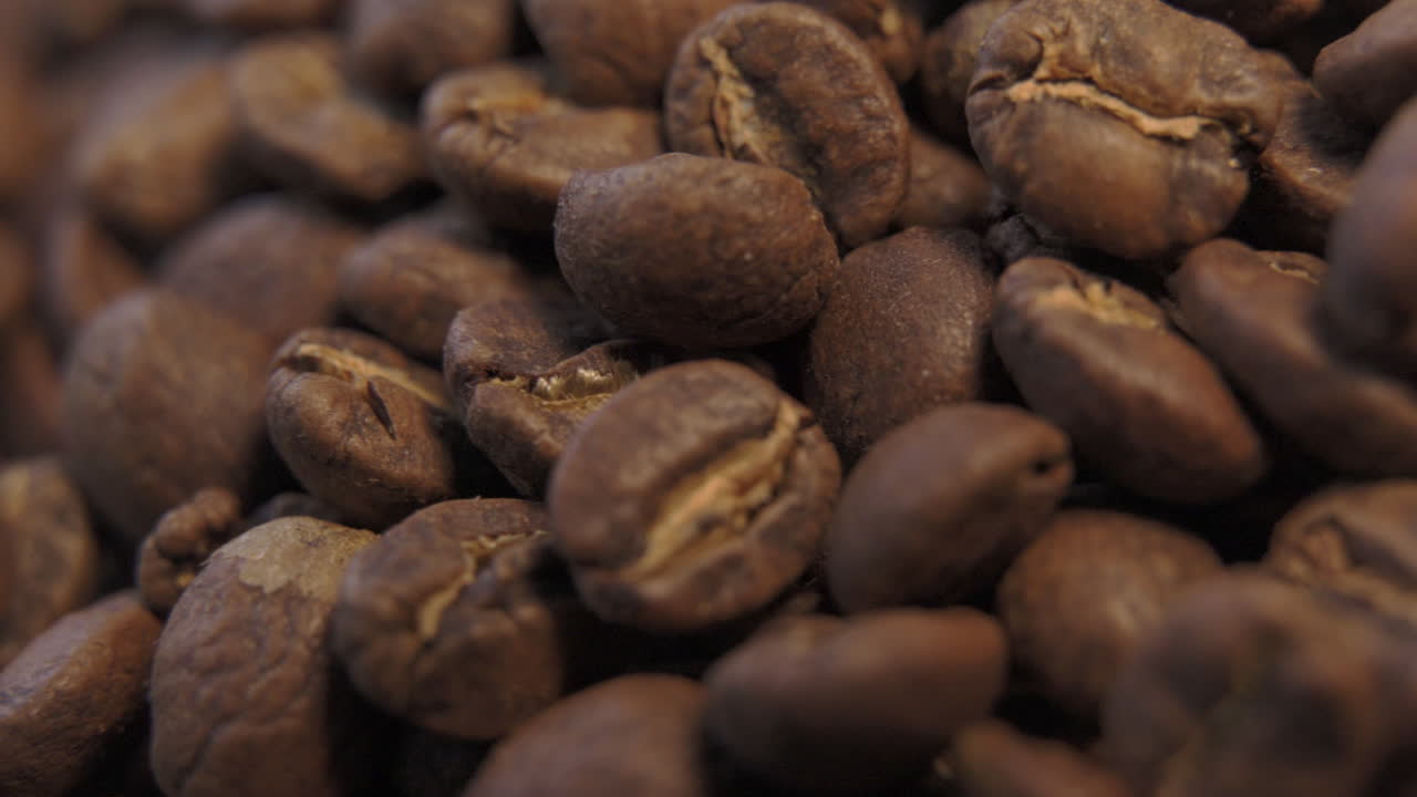 Vista macro ravvicinata di chicchi di caffè marroni appena tostati, da usare per caffè nero caldo, che ruotano a sinistra
