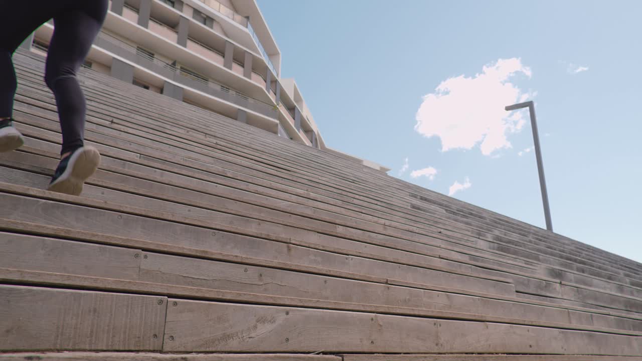 статичный снимок женщины в спортивной одежде, поднимающейся по деревянной лестнице на открытом воздухе