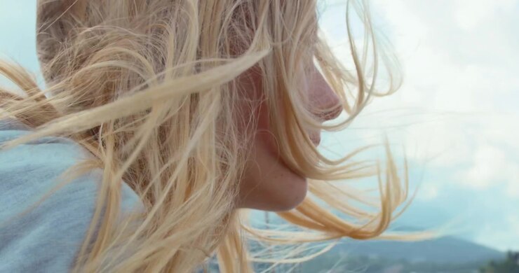 Giovane donna con capelli biondi mossi dal vento