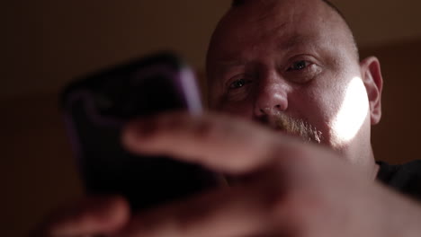 Man-sitting-on-his-couch-texting-on-phone