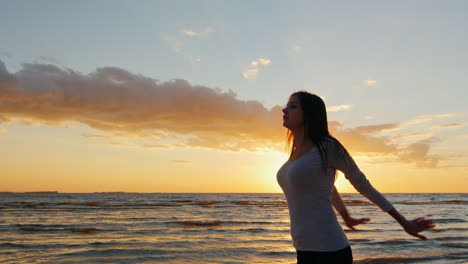 young woman with a beautiful figure warming up before an evening jog on the beach at sunset