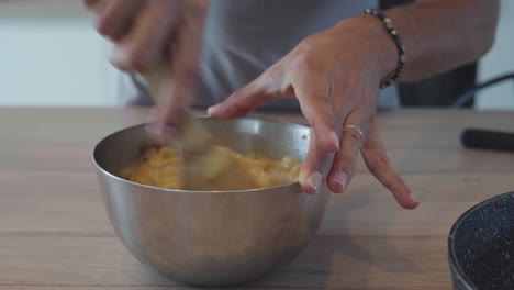 Home-chef-squeezing-lemon-juice-into-eggs-and-melted-butter-mixture-in-bowl