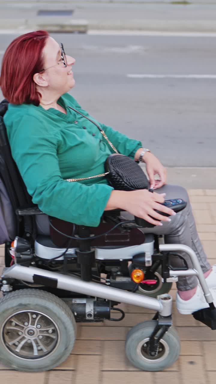 Happy Woman with Red Hair Riding Electric Wheelchair on Sidewalk