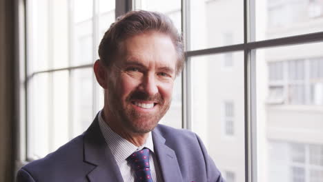 Middle-aged-businessman-turns-and-smiles-to-camera,-close-up