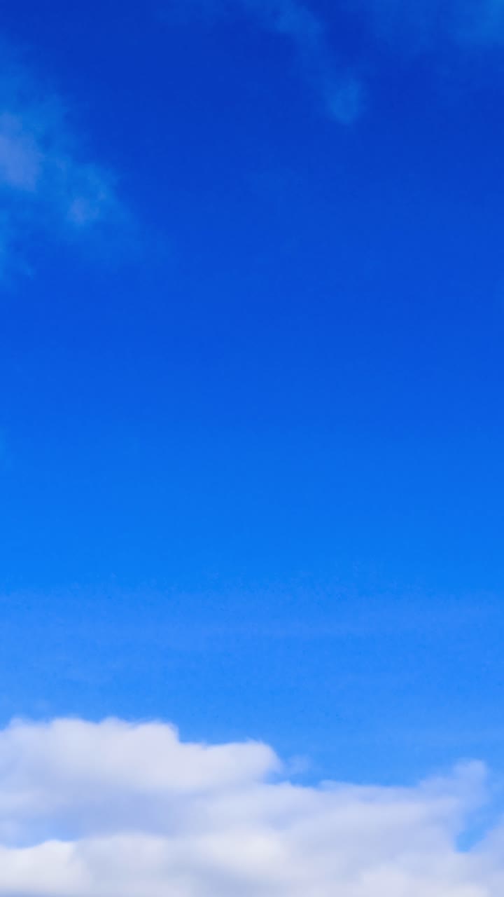 Cielo azul brillante con un suave y esponjoso paisaje de nubes. Nubes cúmulos blancas cambiando rápidamente de forma en la atmósfera. Vista de ángulo bajo. Video vertical