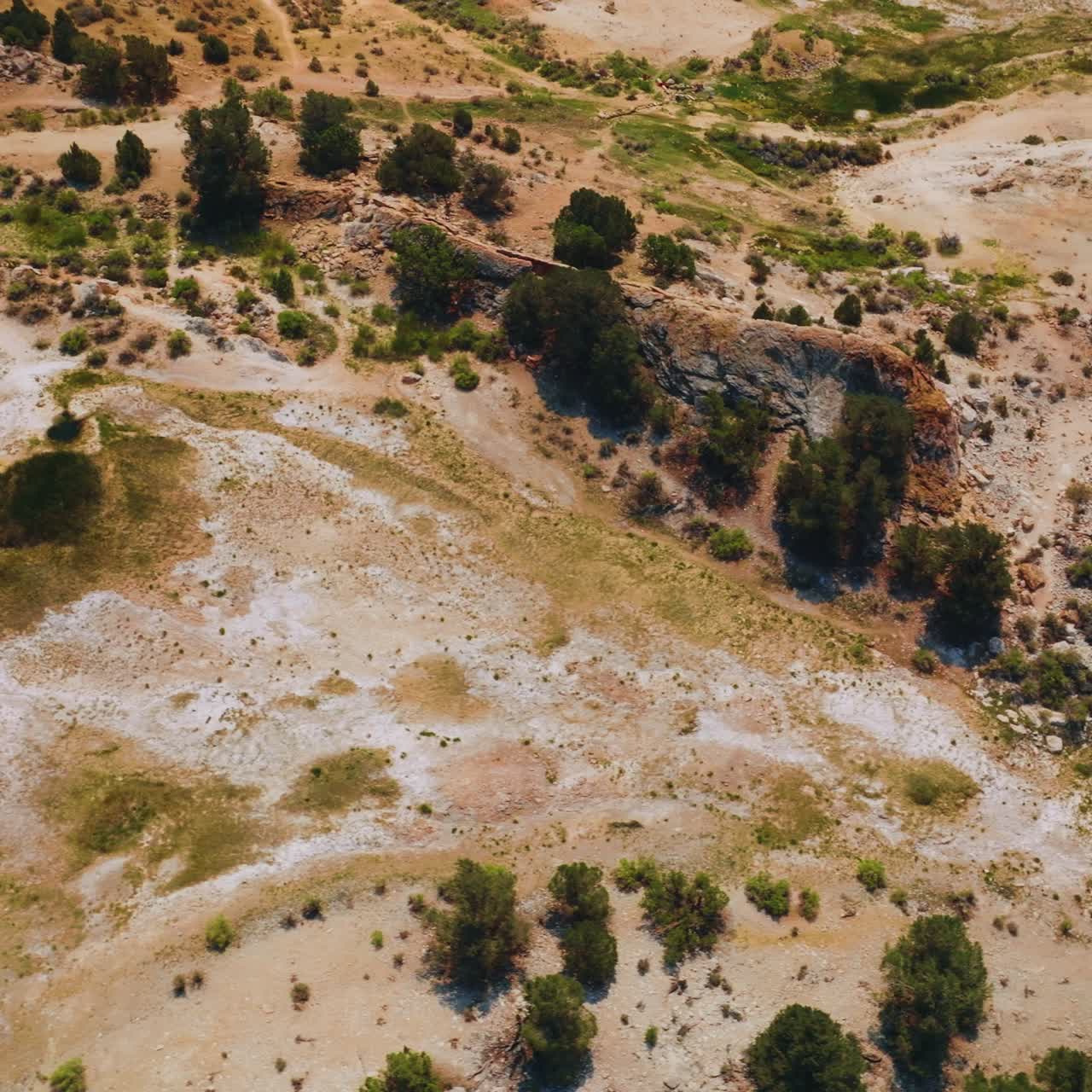 Uneven dry rocky terrain of diverse coloring with scarce vegetation on the surface. Top view on the landscape of Travertine Hot Springs in California, USA