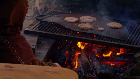 beef patties or sausages grilling on a wood burning outdoor stove