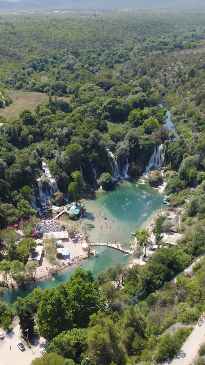 Ripresa con drone delle Cascate di Kravica in Bosnia ed Erzegovina, che mostra una vegetazione lussureggiante e acque blu. Ripresa verticale.