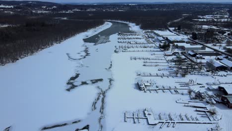 Aerial-drone-footage-of-a-boat-yard-on-a-frozen-river-with-snow-during-winter-in-western-new-York-state