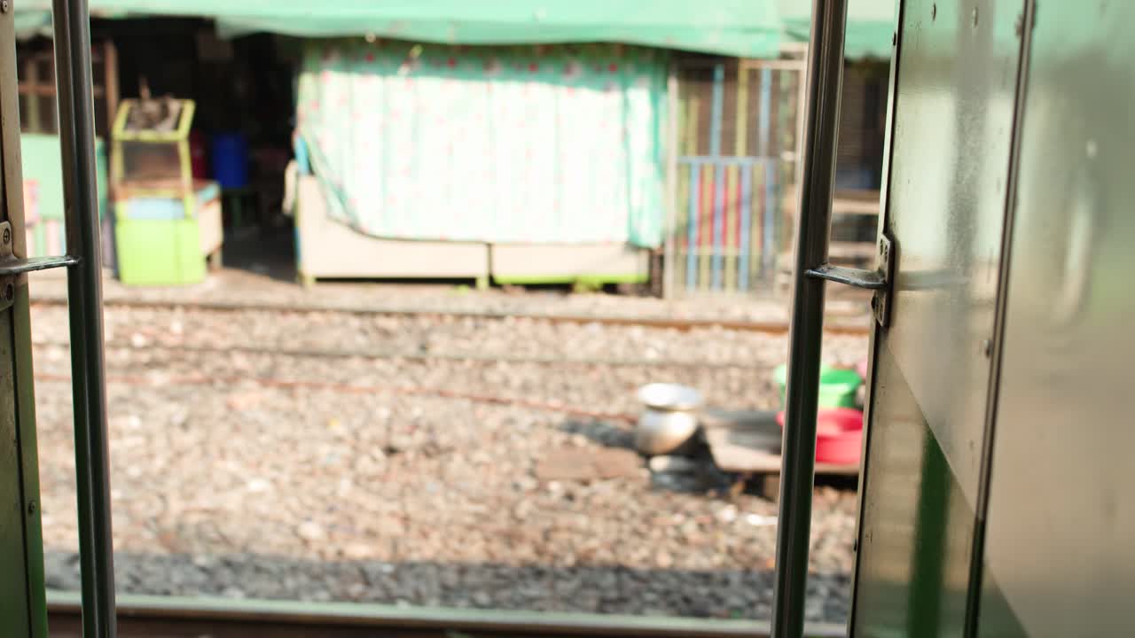 A perspectiva de um trem em movimento mostra edifícios urbanos, grafites e mercados locais sob a luz do dia
