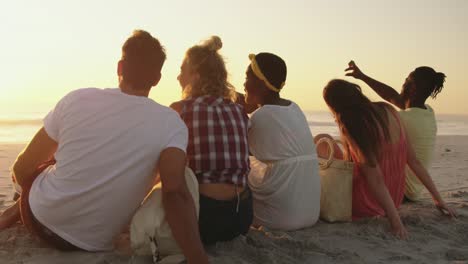 young adult friends relaxing on the beach at sunset 4k